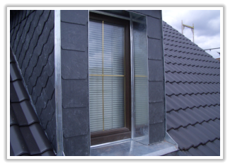 Dachfenster mit Seitenverkleidung auf einem Schieferdach